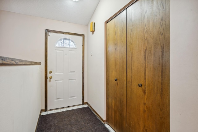entryway featuring baseboards and dark carpet