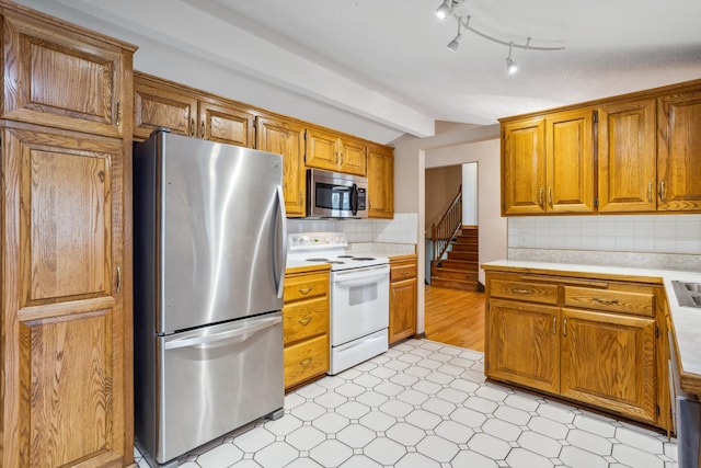 kitchen with brown cabinetry, light floors, light countertops, appliances with stainless steel finishes, and vaulted ceiling