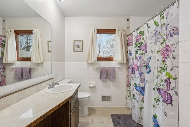 full bath with tile patterned flooring, vanity, plenty of natural light, tile walls, and visible vents