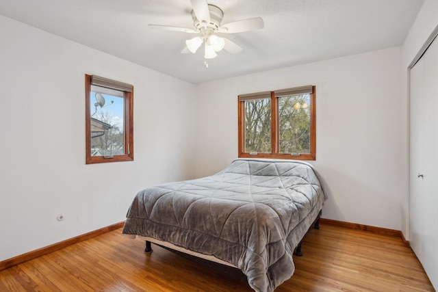 bedroom with baseboards, wood finished floors, and a closet