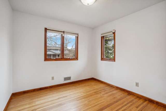 unfurnished room featuring visible vents, baseboards, a wealth of natural light, and light wood-type flooring