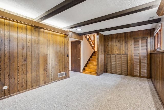 finished below grade area with wooden walls, carpet flooring, visible vents, and stairs