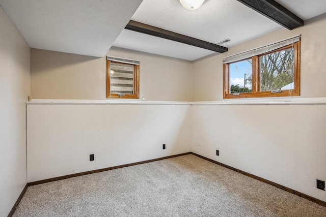 carpeted spare room featuring visible vents, baseboards, and beamed ceiling