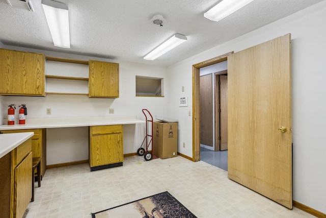 kitchen featuring brown cabinets, open shelves, light countertops, baseboards, and light floors