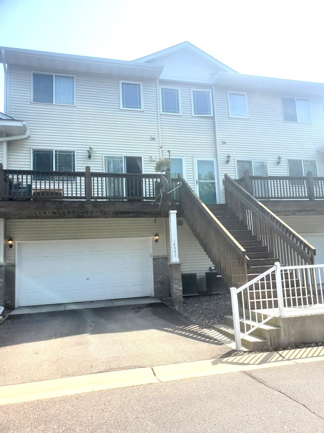 back of property with stairway, aphalt driveway, and a garage