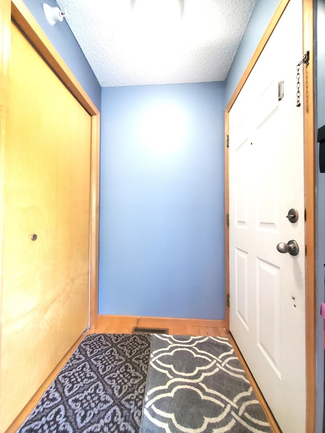 doorway featuring a textured ceiling and baseboards