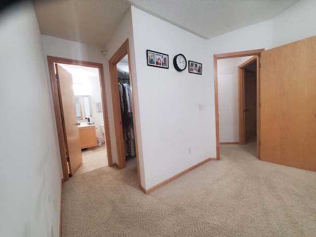 hall with baseboards and light colored carpet