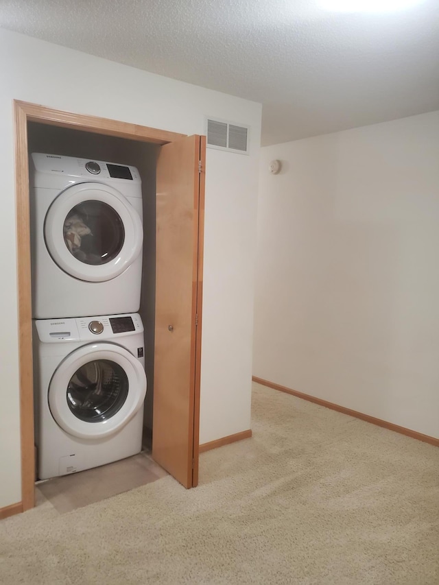 laundry area featuring stacked washer / drying machine, visible vents, baseboards, carpet, and laundry area