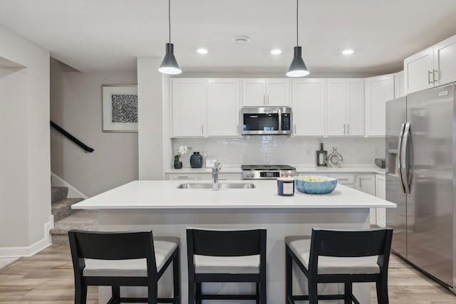 kitchen featuring decorative backsplash, light wood-style flooring, appliances with stainless steel finishes, and a breakfast bar