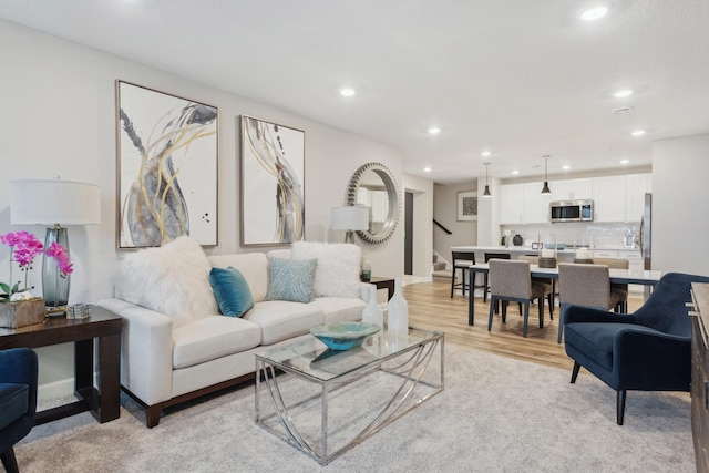 living room with recessed lighting, light wood-style floors, and stairway
