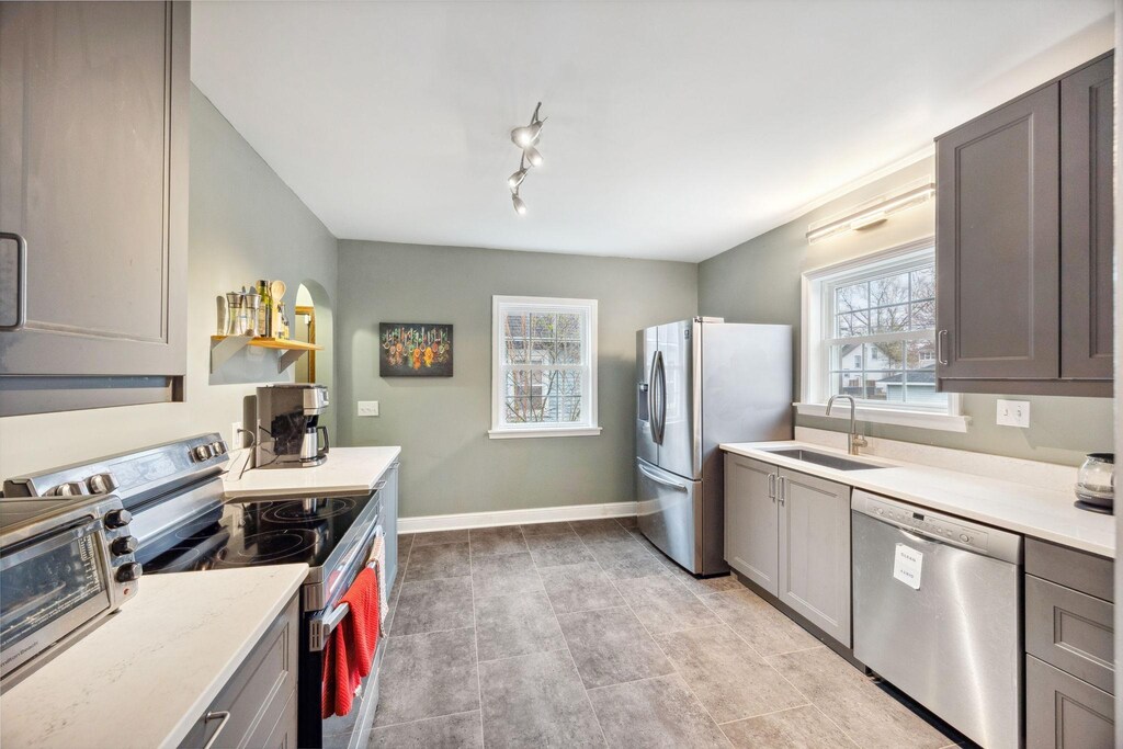 4007 Dupont Ave N, Minneapolis, MN 55412 - kitchen with baseboards, a sink, gray cabinets, and appliances with stainless steel finishes