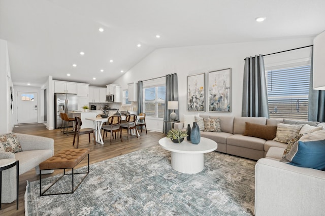living room featuring recessed lighting, light wood finished floors, and high vaulted ceiling