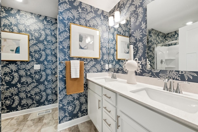 bathroom with a sink, walk in shower, double vanity, and visible vents