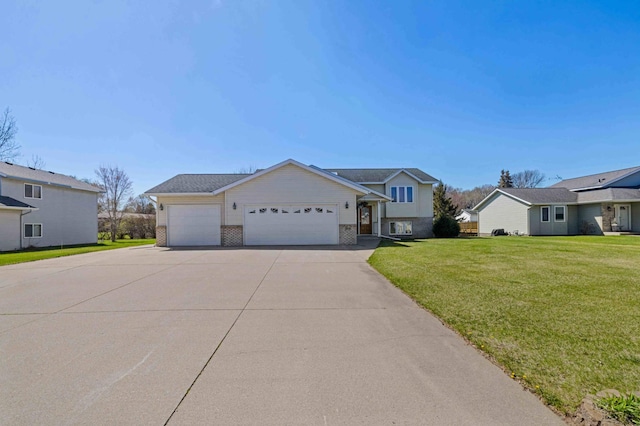 split level home with brick siding, an attached garage, driveway, and a front yard