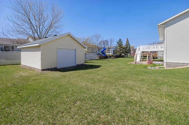 view of yard with a detached garage, fence, an outbuilding, and a wooden deck