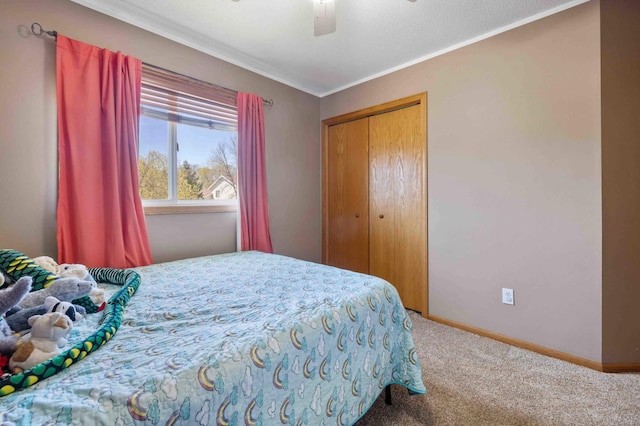 carpeted bedroom featuring crown molding, baseboards, ceiling fan, and a closet