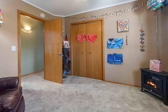 carpeted bedroom featuring crown molding, baseboards, a wood stove, and a closet