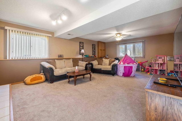 carpeted living area featuring track lighting, ceiling fan, and visible vents