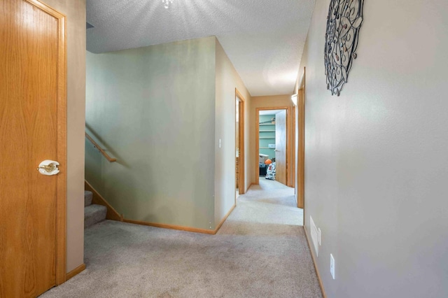 hallway with baseboards, carpet flooring, and a textured ceiling