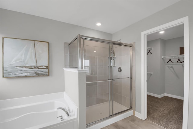 full bathroom with a garden tub, a shower stall, baseboards, and a walk in closet