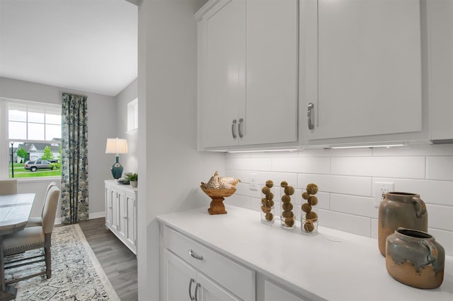 kitchen with baseboards, tasteful backsplash, light wood-style floors, light countertops, and white cabinetry