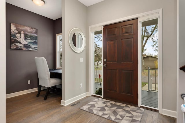 foyer featuring baseboards, visible vents, and wood finished floors
