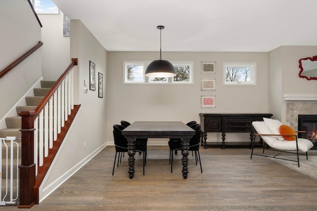 dining area with stairs, baseboards, wood finished floors, and a fireplace