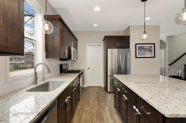 kitchen with a sink, dark brown cabinets, appliances with stainless steel finishes, and dark wood-type flooring