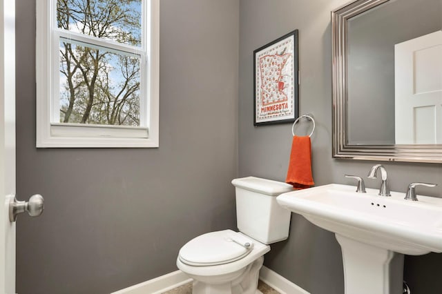 half bathroom featuring a sink, toilet, and baseboards
