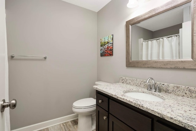 full bathroom with baseboards, wood finished floors, toilet, and vanity