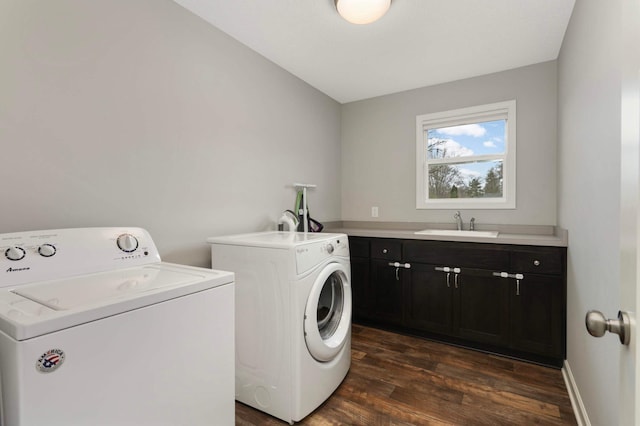 laundry room featuring dark wood-type flooring, washer and dryer, cabinet space, and a sink
