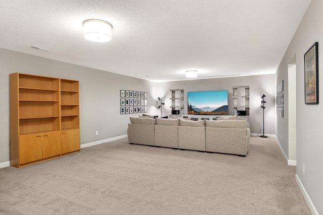 living area with baseboards, visible vents, light carpet, and a textured ceiling
