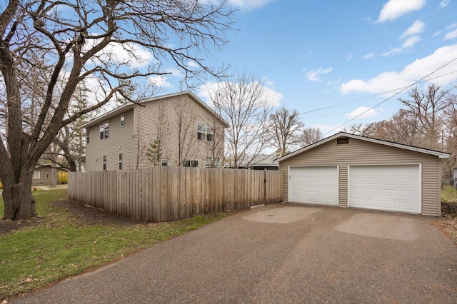 view of home's exterior featuring an outdoor structure, a garage, and fence