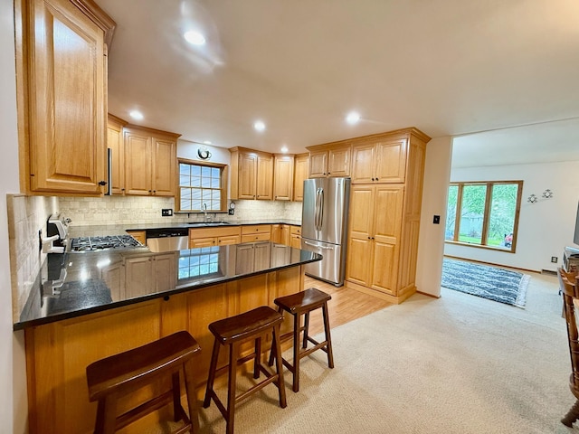 715 Crest Ln, Ellsworth, WI 54011 - kitchen with appliances with stainless steel finishes, a sink, light carpet, a peninsula, and decorative backsplash