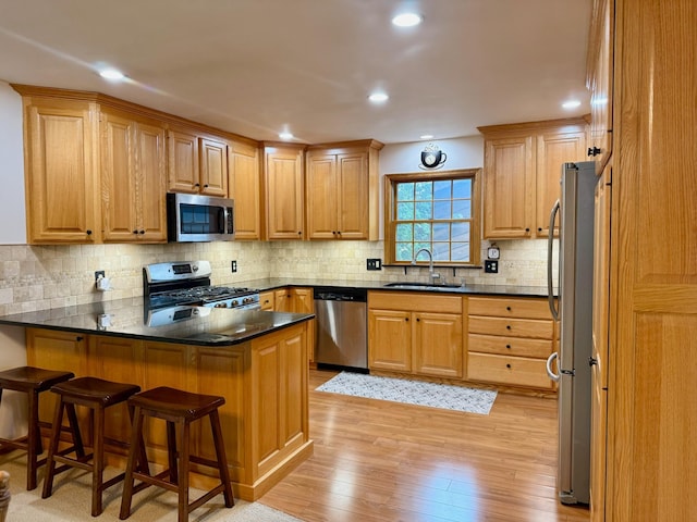 715 Crest Ln, Ellsworth, WI 54011 - kitchen featuring appliances with stainless steel finishes, a sink, a peninsula, light wood-type flooring, and a breakfast bar area