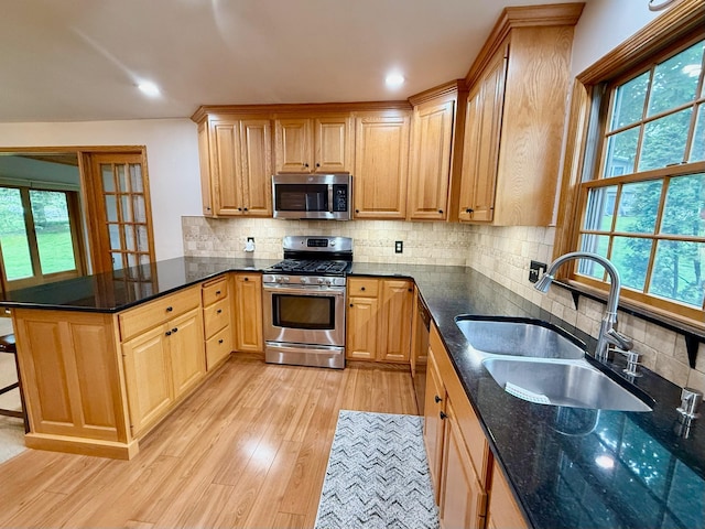 715 Crest Ln, Ellsworth, WI 54011 - kitchen with appliances with stainless steel finishes, a sink, light wood-style flooring, a peninsula, and tasteful backsplash