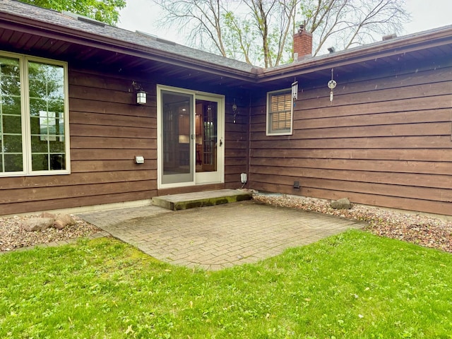 715 Crest Ln, Ellsworth, WI 54011 - property entrance featuring a chimney, a lawn, and a patio area