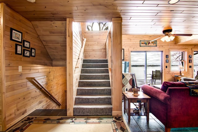 stairway featuring a ceiling fan, wooden walls, and wooden ceiling