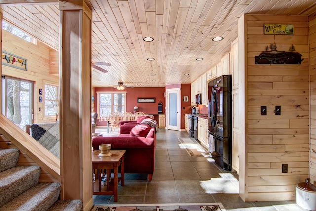 living room with a ceiling fan, recessed lighting, wood ceiling, dark tile patterned floors, and wood walls