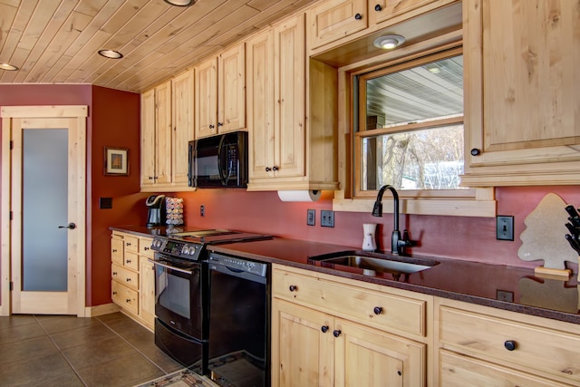 kitchen with dark tile patterned floors, a sink, dark countertops, light brown cabinets, and black appliances