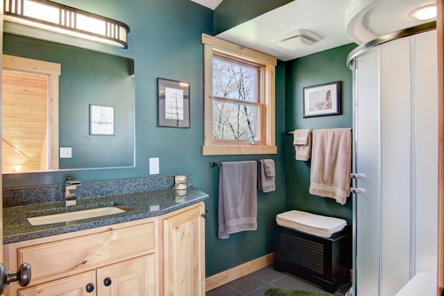 bathroom with tile patterned flooring, baseboards, a shower stall, and vanity