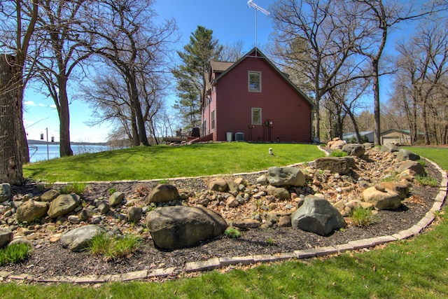 view of side of property featuring a yard, a water view, and central AC