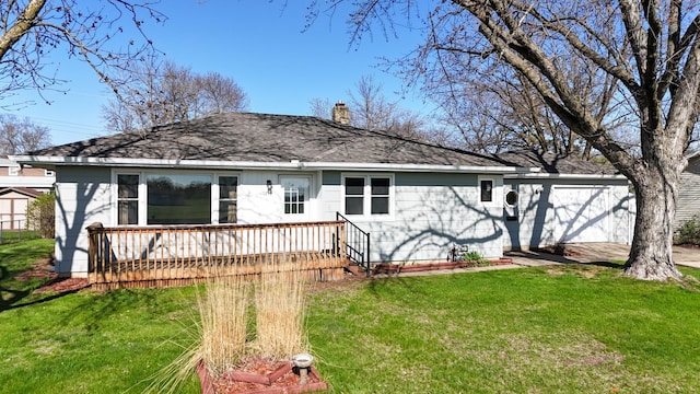 back of property with a shingled roof, a chimney, a yard, and a deck