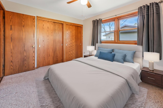 bedroom featuring two closets, ceiling fan, and carpet