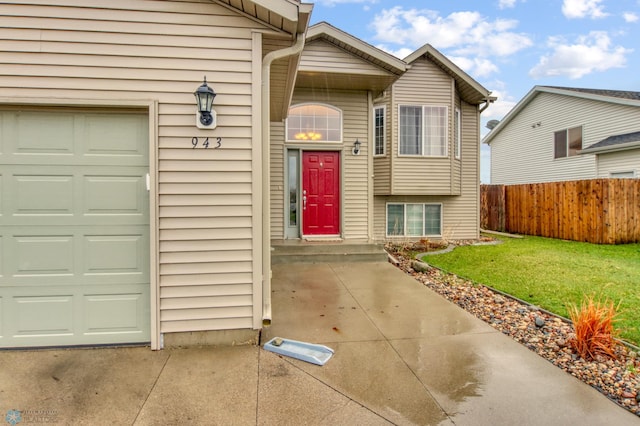 entrance to property with a lawn, fence, and a garage