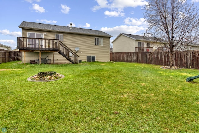 back of property with a fire pit, a deck, a fenced backyard, stairs, and a yard