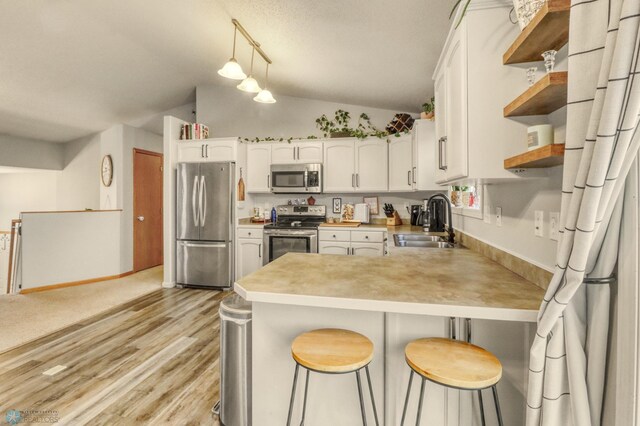 kitchen featuring open shelves, a sink, stainless steel appliances, a peninsula, and vaulted ceiling