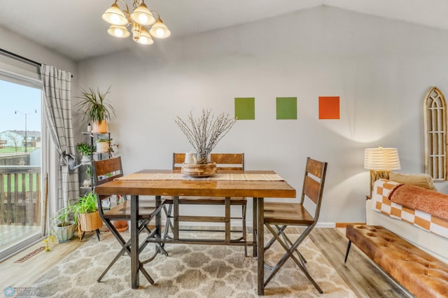 dining room featuring an inviting chandelier, wood finished floors, and vaulted ceiling