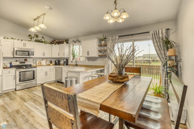 kitchen with an inviting chandelier, lofted ceiling, light countertops, a sink, and stainless steel appliances
