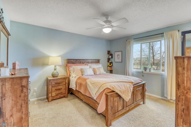 bedroom with a textured ceiling, baseboards, light colored carpet, and ceiling fan